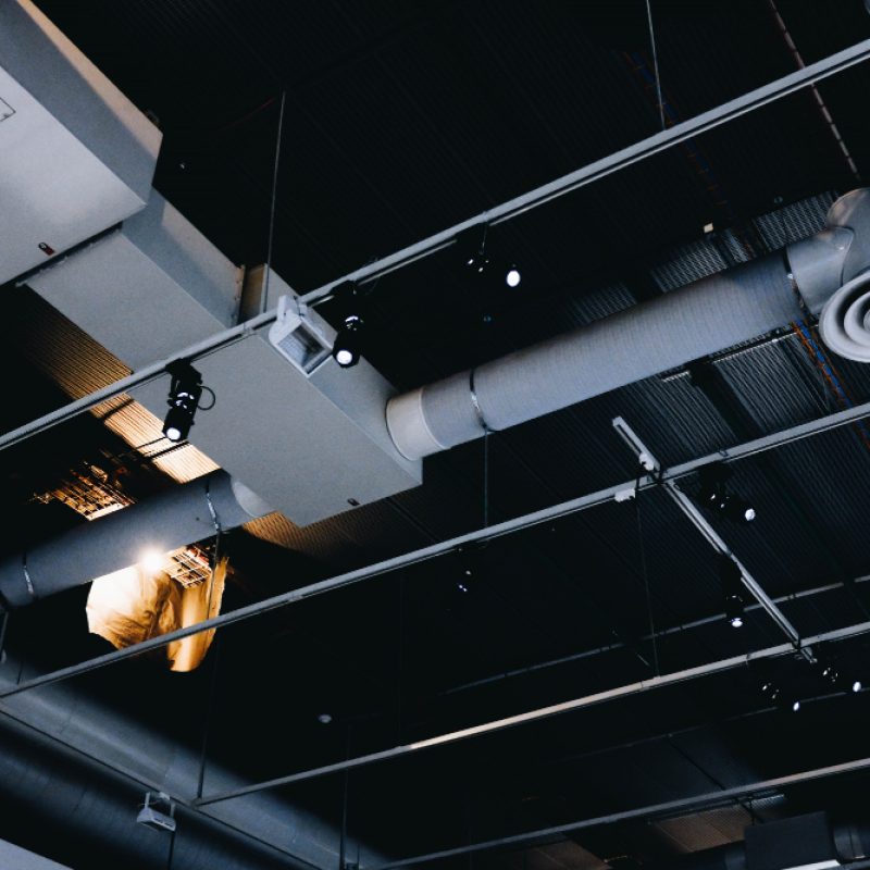 low-angle-shot-metal-black-ceiling-with-white-ventilation-pipes
